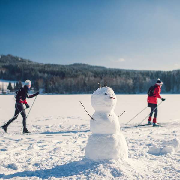 Běžkaři na zmrzlém Lipně v popředí se sněhulákem