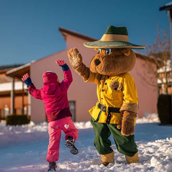 Maskot medvěd Bollo si dává s holčičkou high five v resortu Landal Marina Lipno