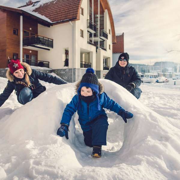 Rodina si hraje na sněhu před apartmány Marina Lipno