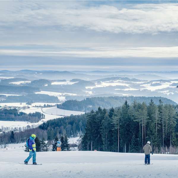 Lyžaři na sjezdovce s panoramatickým výhledem