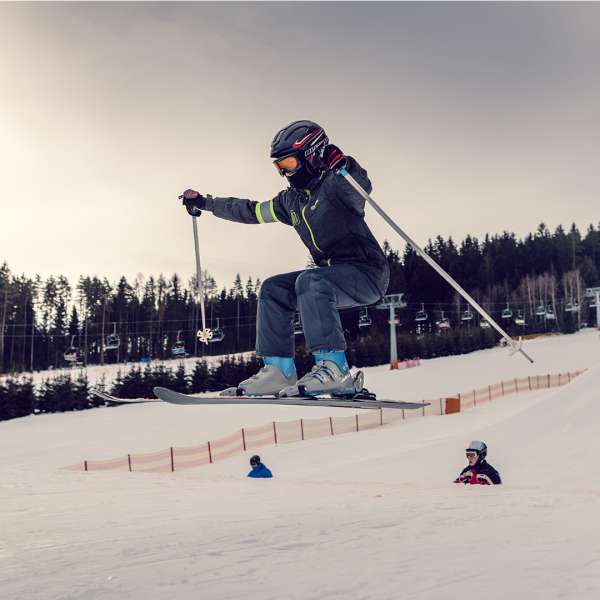 Lyžař který letí po skoku na překážce snowparku Lipno