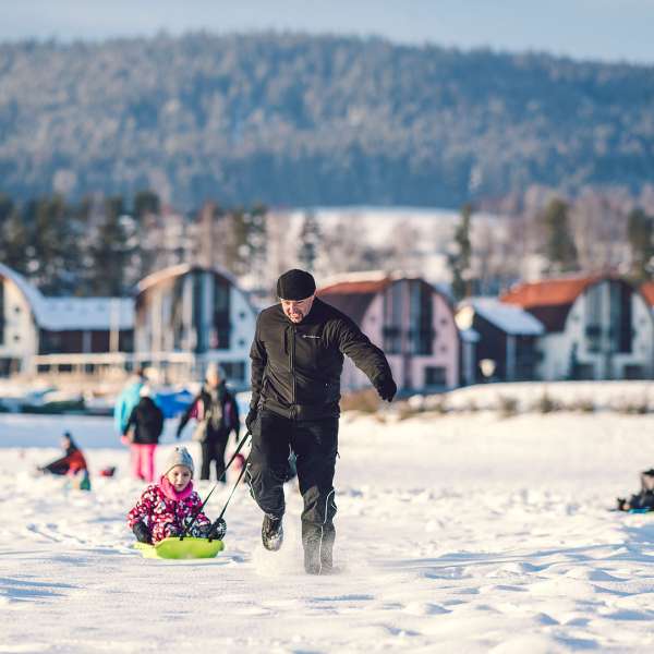 Děti si hrají a jezdí na bobech na zamrzlém a zasněženém Lipně 