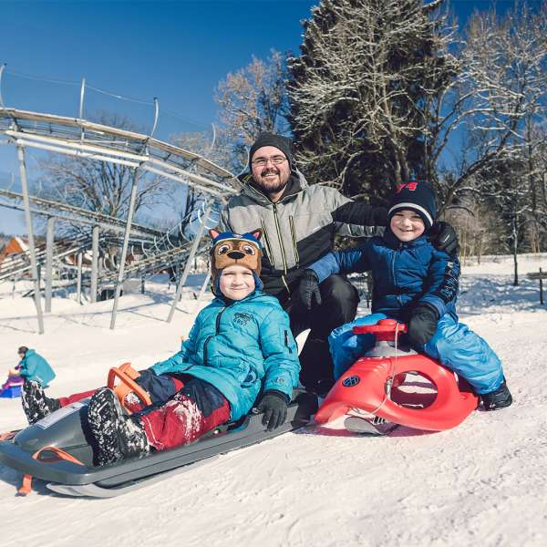 Děti s tatínkem na bobech před Horskou bobové dráhy Lipno