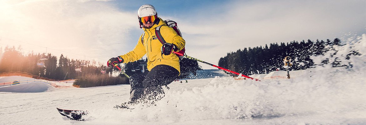 Skiareál Lipno lyžař ve žluté bundě na sjezdovce Skiareálu Lipno