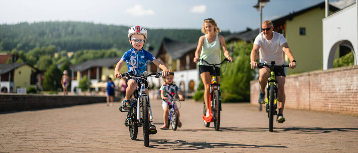 Rodina na kolech a koloběžce na jezerní cyklostezce v Landal Marina Lipno